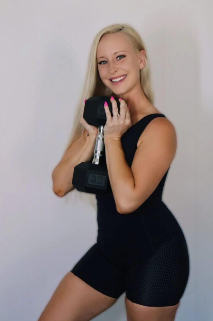 A woman in black dress holding two dumbbells.