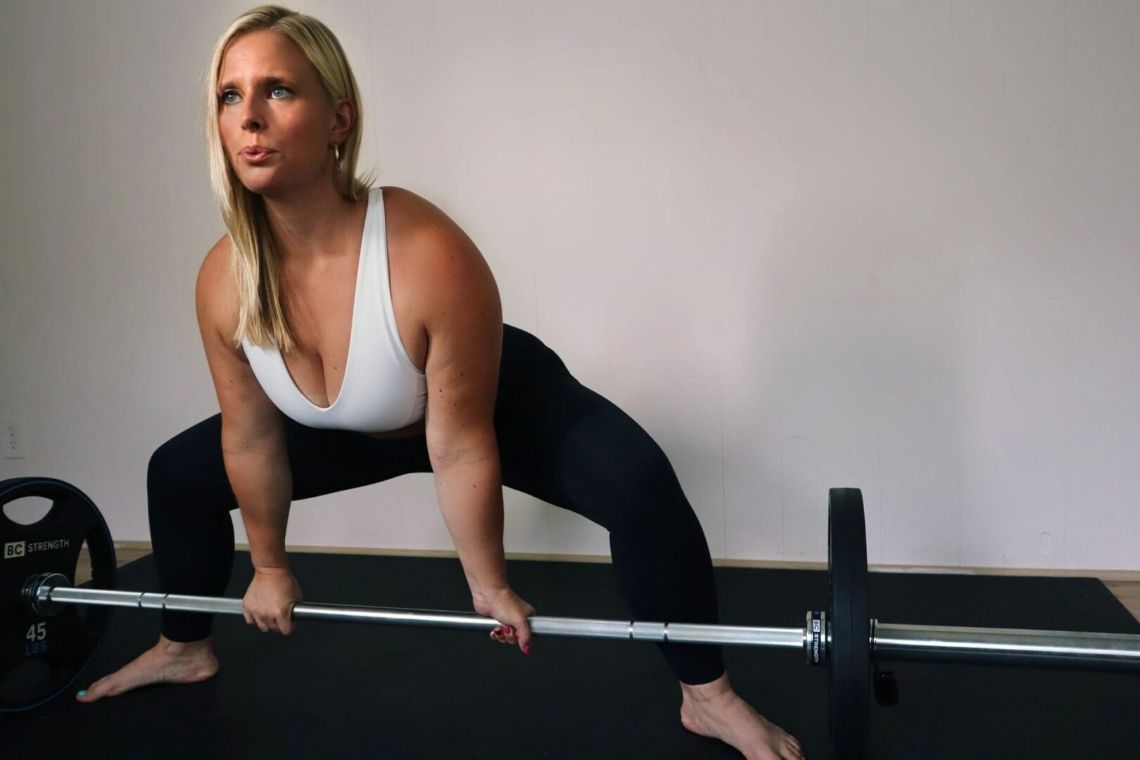 A woman is squatting with a barbell in her hands.