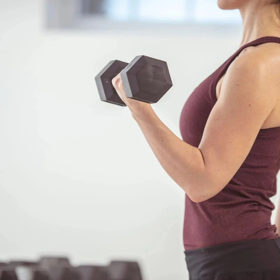 A woman is holding a black dumbbell in her hand.